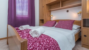 A bedroom with a bed, wooden wardrobe, and a window with purple curtains. - Apartment mit zwei Schlafzimmern und eigenem Balkon by Interhome (Trogir/Okrug Donji)