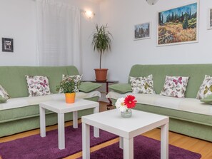 A living room with a green sofa, white coffee table, and a potted plant. - "Emelie" mit Blick auf das Wasser by Interhome (Trogir/Okrug Donji)