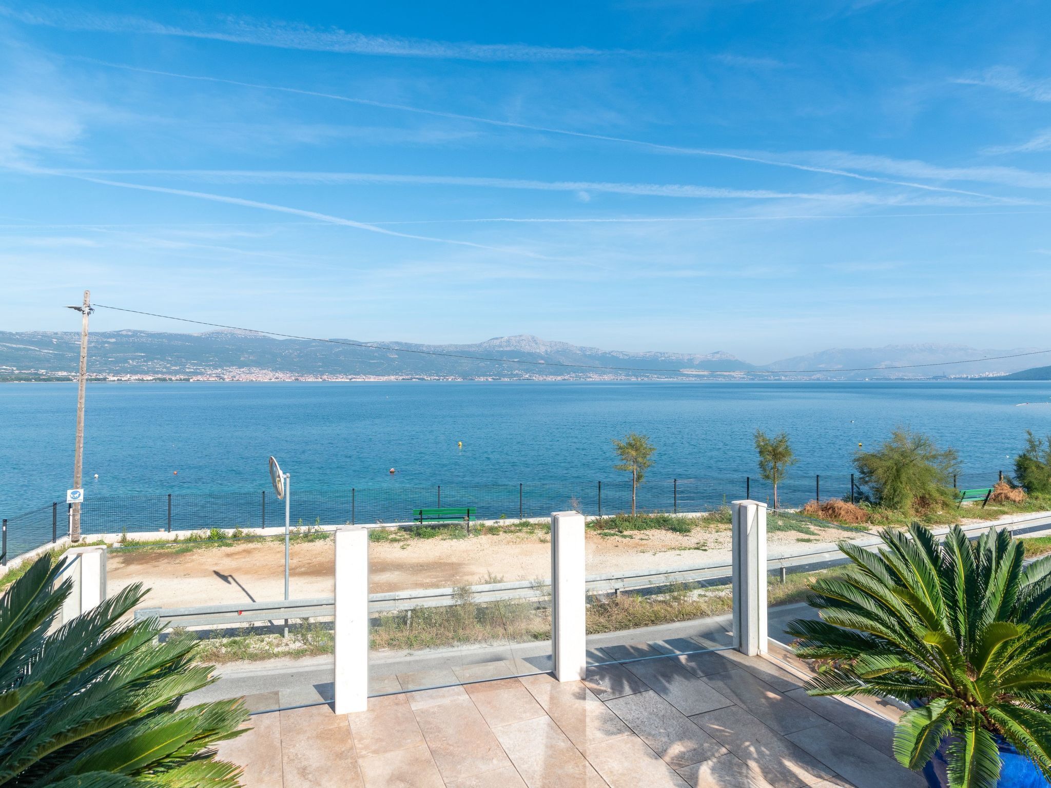 A coastal view with a clear sky, a body of water, and a distant cityscape.