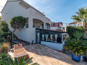 Um edifício moderno com área de estar coberta ao ar livre, um restaurante visível e uma escadaria de pedra que leva a um andar superior.