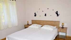 Un dormitorio con una cama de madera, ropa de cama blanca, dos mesitas de noche con lámparas y decoración de mariposas en la pared.