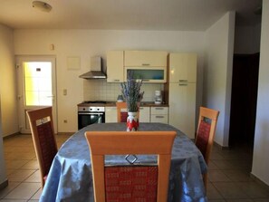 Een kleine keuken met een eettafel, stoelen en een vaas met bloemen.