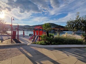 A playground with slides and a climbing structure near a body of water with boats and a hill in the background. - Wohnung in Marina mit Parkplatz, schöne Aussicht by Interhome (Marina)