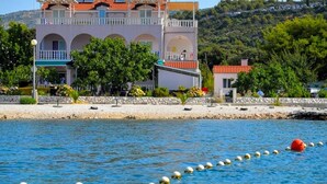 Un edificio costero con balcón, muro de piedra y vista despejada al mar.