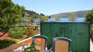 Una terraza con una mesa y sillas, con vistas a un lago y colinas.
