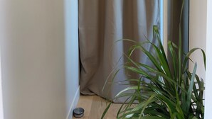 A narrow hallway with a beige curtain, a potted plant, and a telephone mounted on the wall. - Cosy bed Montparnasse (Paris)
