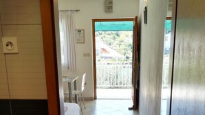 Ein Hotelzimmer mit Balkon, einem Bett, einem Schreibtisch und einem Stuhl.