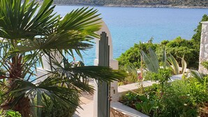 A coastal view with a stone wall, a palm tree, and a variety of plants. - mit Blick auf das Wasser by Interhome (Podorljak)