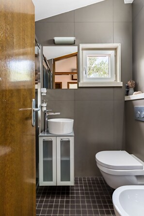 A modern bathroom with a white sink, a toilet, and a window above the sink. - mit Blick auf das Wasser by Interhome (Podorljak)
