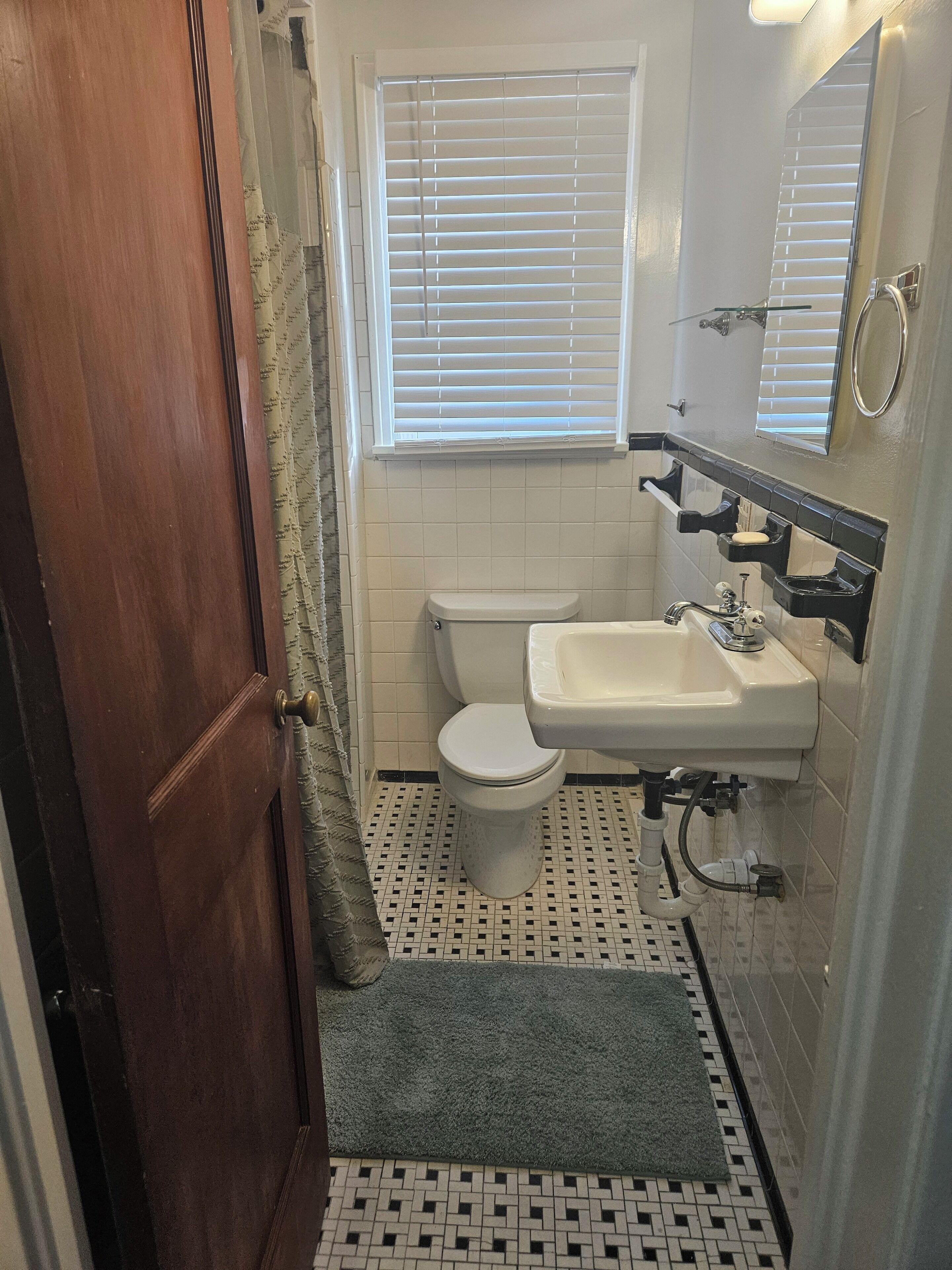 A bathroom with a toilet, sink, and window with blinds.