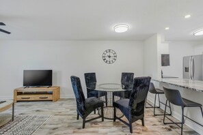 A modern kitchen with a round dining table, black upholstered chairs, a flat-screen TV, and a built-in refrigerator. - Modern 2BR in South Tampa with Pool, Parking & Workspace (Tampa)