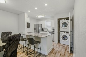 A modern kitchen with white cabinets, a marble island, and a built-in washer and dryer. - Modern 2BR in South Tampa with Pool, Parking & Workspace (Tampa)