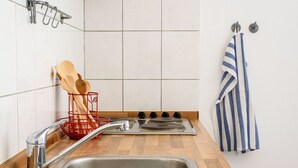 Una cocina con un lavamanos de acero inoxidable, encimera de madera y un portalapices rojo.