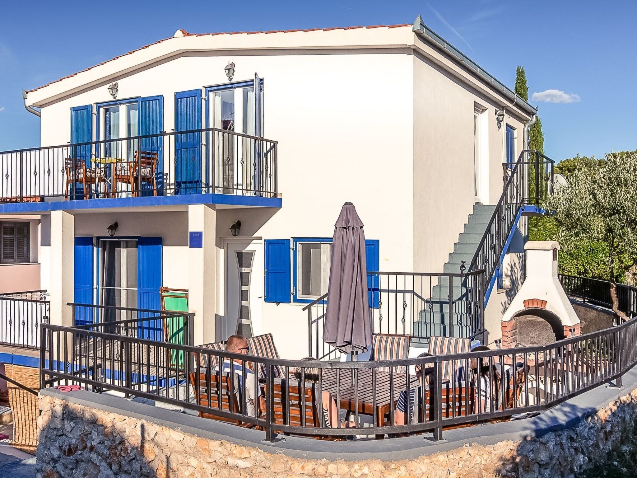 A two-story building with a balcony, outdoor seating area, and a staircase.