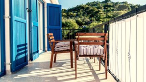 A balcony with two wooden chairs and a table, overlooking a lush green hillside. - in Tisno mit Terrasse und Grill by Interhome (Tisno)