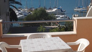 Een balkon met een tafel en stoelen, uitkijkend op een jachthaven met boten.