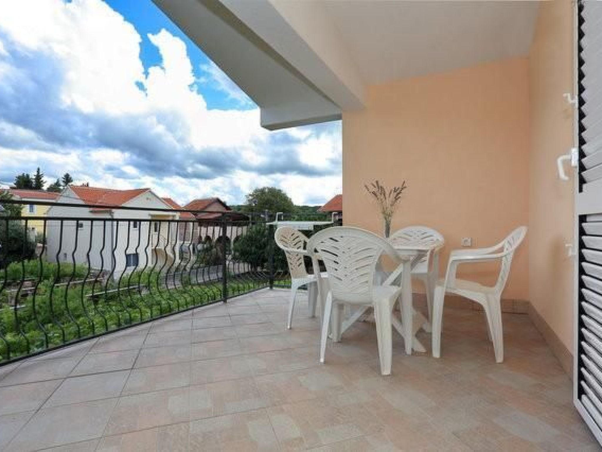 Un balcon avec une table et des chaises, une vue sur des maisons et une clôture.