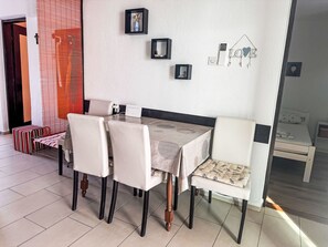 A dining area with a table and chairs, a wall-mounted light switch, and a small shelf with decorative items. - mit überdachter Terrasse und Meerblick by Interhome (Drage)