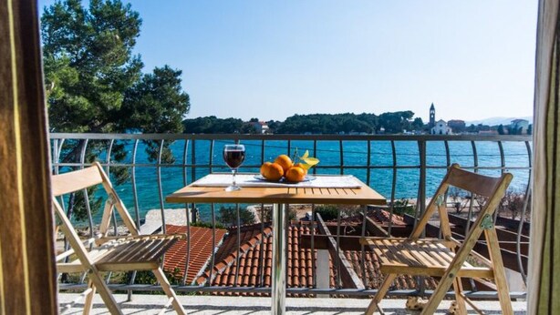 A balcony with a table, two chairs, and a glass of wine. - Wohnung "Mama Roza" mit Blick auf das Wasser by Interhome (Pašman/Pašman)