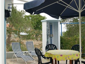 Eine Terrasss mit zwei gestreiften Liegestühlen, einem Tisch mit gelber Tischdecke und einer Fontäne.