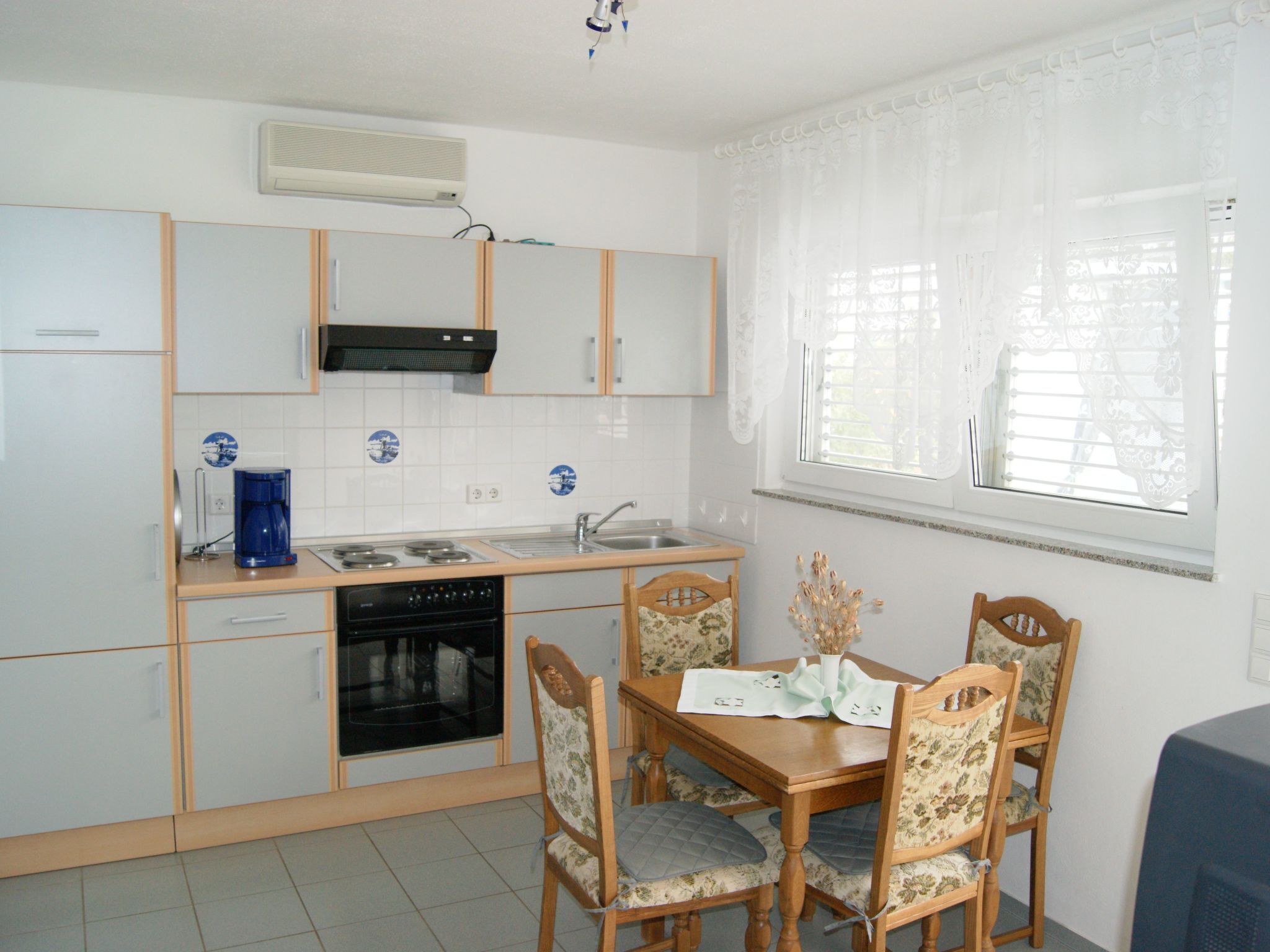 Cocina compacta con estufa, pileta y una mesa de comedor con sillas.