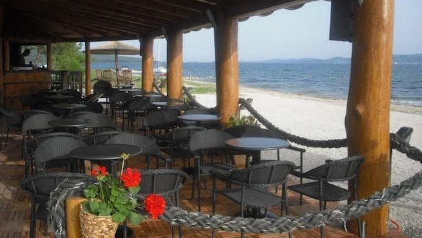 A covered outdoor seating area with tables and chairs, overlooking a beach and the sea. - Studio-Apartment mit Balkon und Meerblick by Interhome (Debeljak)
