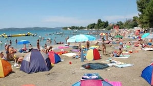 A crowded beach with multiple colorful tents and umbrellas. - Studio-Apartment mit Balkon und Meerblick by Interhome (Debeljak)