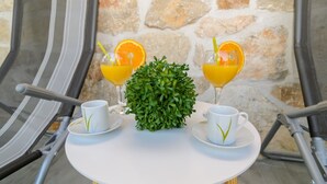 Taula amb dues tasses blanques, dues flautes d'aigua de taronja, una petita planta verda i una cadira amb tires.
