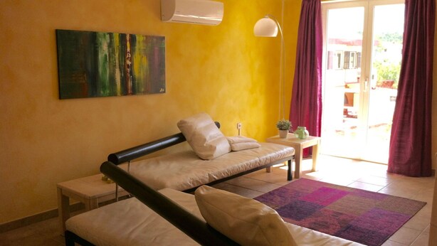 Une pièce comprenant un lit, un canapé, une petite table, une lampe et un tableau accroché au mur.