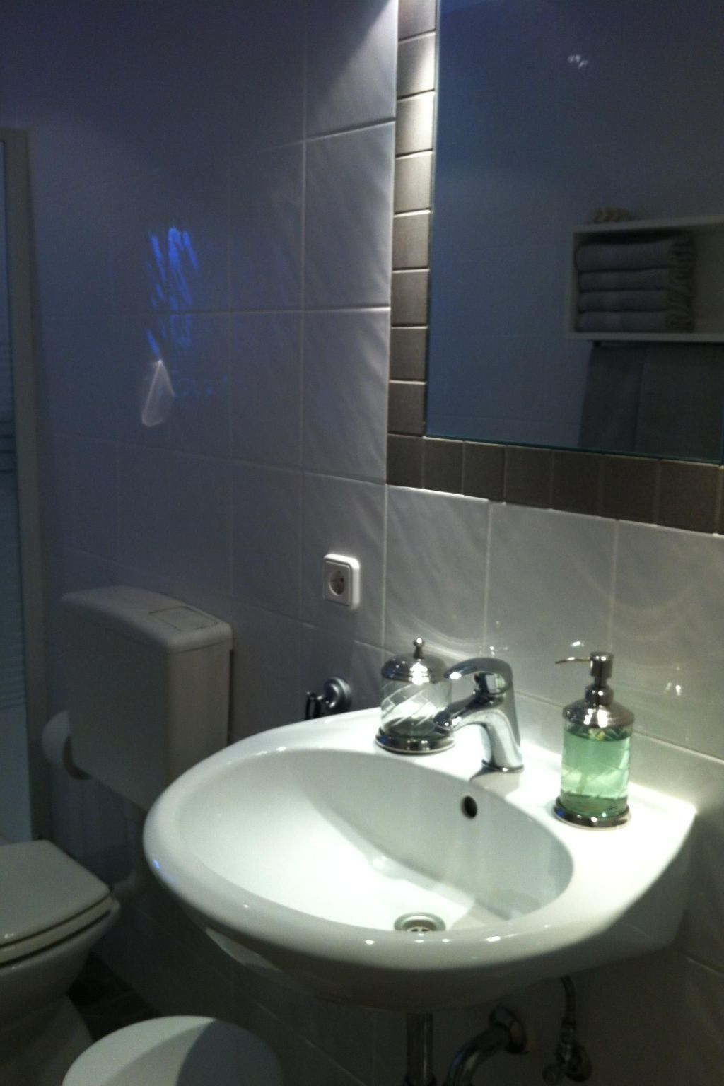 A bathroom with a white sink, a mirror, and a toilet.