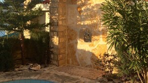 A stone pool with a tiled edge, surrounded by a stone patio and a pergola with solar panels. - Wohnung in Novigrad mit Möblierter Terrasse by Interhome (Novigrad (Zadar))