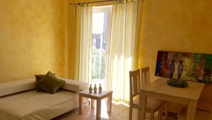 A room with a sofa, a small table, and a dining table with chairs. - Wohnung in Novigrad mit Möblierter Terrasse by Interhome (Novigrad (Zadar))