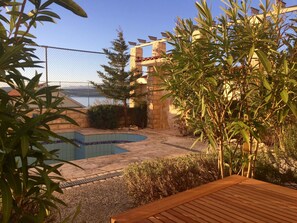 A swimming pool with a tiled edge, surrounded by a wooden deck, a stone wall, and a fence. - Erdgeschossferienwohnung Domicil Adria by Interhome (Novigrad (Zadar))
