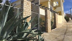 Edifici residencial amb façana de pedra, tanca metàl·lica i cel serè.