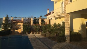 Ein Wohngebäude mit Pool, Steinsäulen und blauem Himmel.