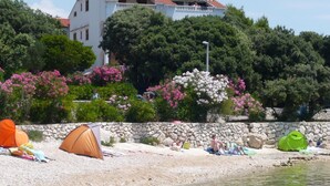 A beach with tents and a stone wall. - Mia Mandre für vier Personen by Interhome (Kolan)