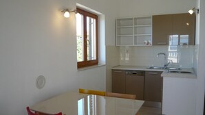 A compact kitchen with a dining area, featuring a window, cabinets, and a dishwasher. - Mia Mandre für vier Personen by Interhome (Kolan)