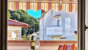 Un balcon avec une table, deux chaises, une bouteille de vin et un verre.