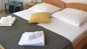 Een hotelkamer met een bed, kussens, een nachtkastje met een lamp, een bijzettafeltje met een lamp en kunst aan de muur.