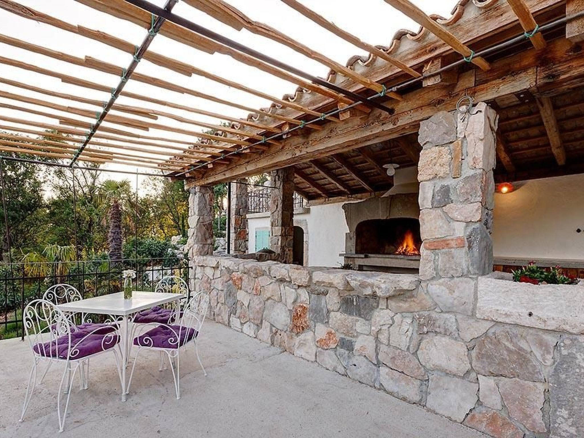 An outdoor patio with a stone fireplace, a table, and chairs.