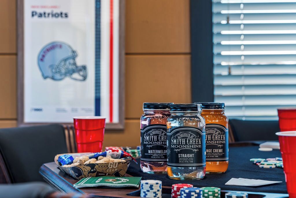 A poker table with chips, cards, and jars of Smith Creek Moonshine.