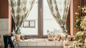Uma cozinha com janela, cafeteira e utensílios na bancada.