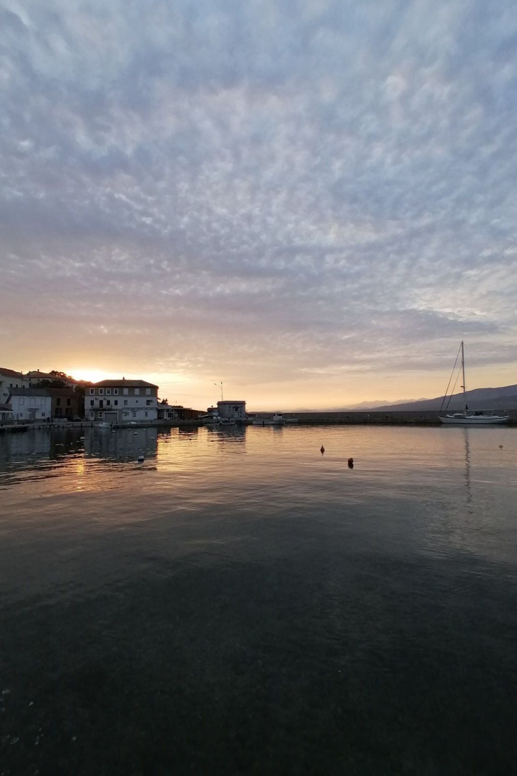 A calm waterfront with buildings and a boat docked on the right.