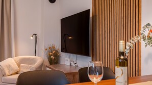 Una sala de estar moderna con una televisión de pantalla plana, un panel de pared de madera, un sofá, una mesa de centro y una botella de vino.