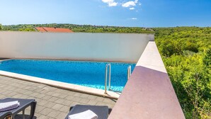 Una piscina en la azotea con agua cristalina, rodeada de sillones de descanso y un gran paraguas.