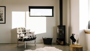 Una sala de estar acogedora con chimenea, un sillón estampado, una alfombra mullida y un taburete de madera rústica.