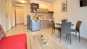 Kompakti oleskelutila, jossa on pieni keittiö, ruokailualue ja oleskelualue.