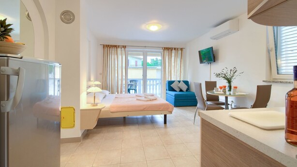 Ein modernes Hotelzimmer mit Bett, Schreibtisch, Stuhl, Fernseher und einem Balkon mit Vorhängen.
