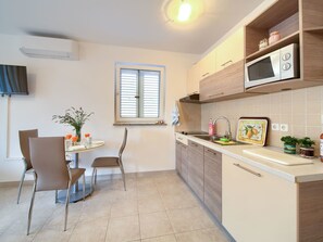A compact kitchen with a dining area, featuring a microwave, sink, and a small table with chairs. - Studio-Apartment A6 im Erdgeschoss by Interhome (Krk/Šilo)