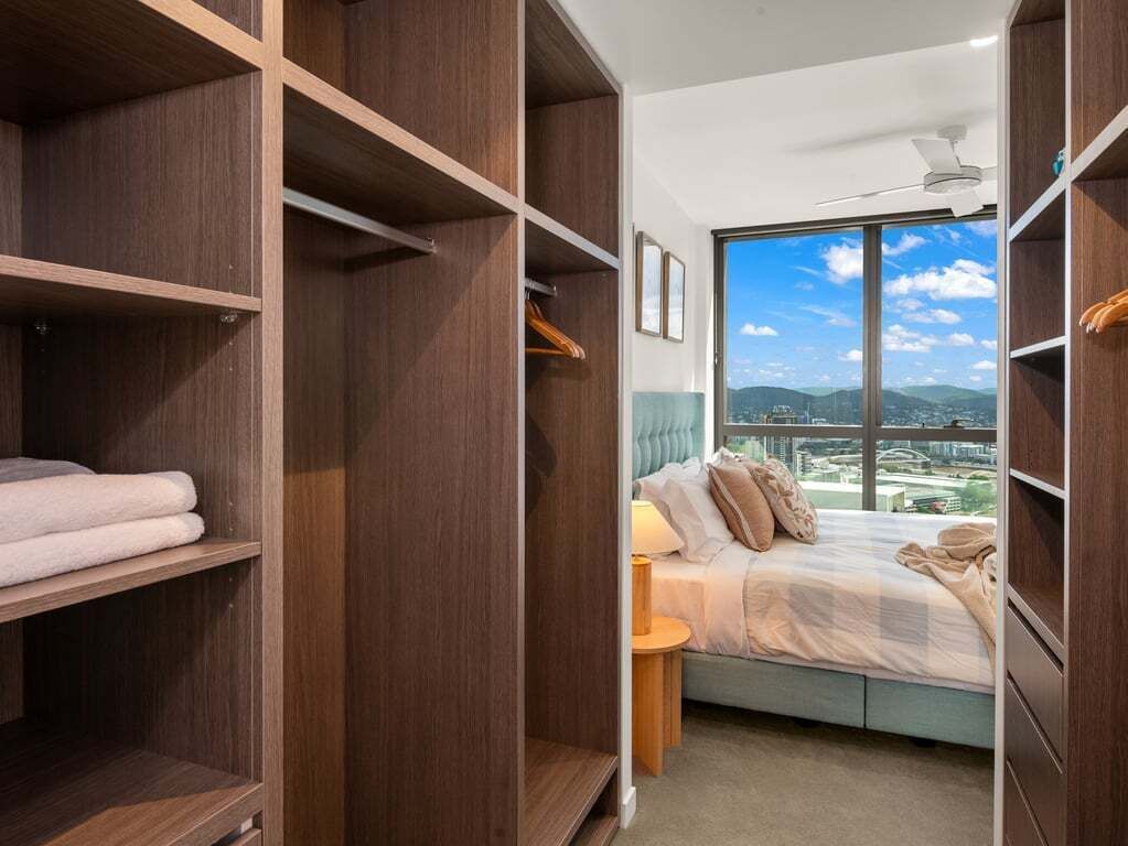 Ein Schlafzimmer mit großem Fenster, einem Bett und Holzregalen.